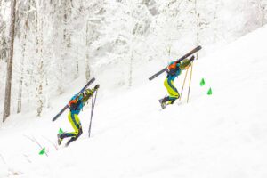 Competiție sportivă iarna în Poiana Brașov - schiori alergând la deal